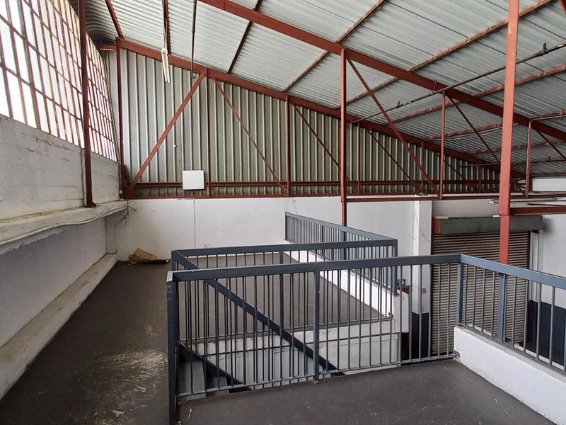 Industrial mezzanine level featuring exposed steel structural beams, metal roofing, and safety railings, suitable for storage or additional workspace.