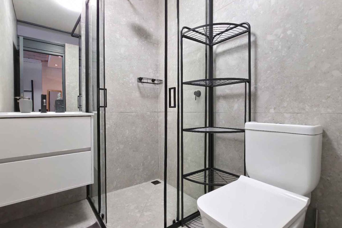 Modern bathroom featuring a walk-in shower with black-framed glass, wall-mounted vanity, and contemporary neutral tiling throughout.