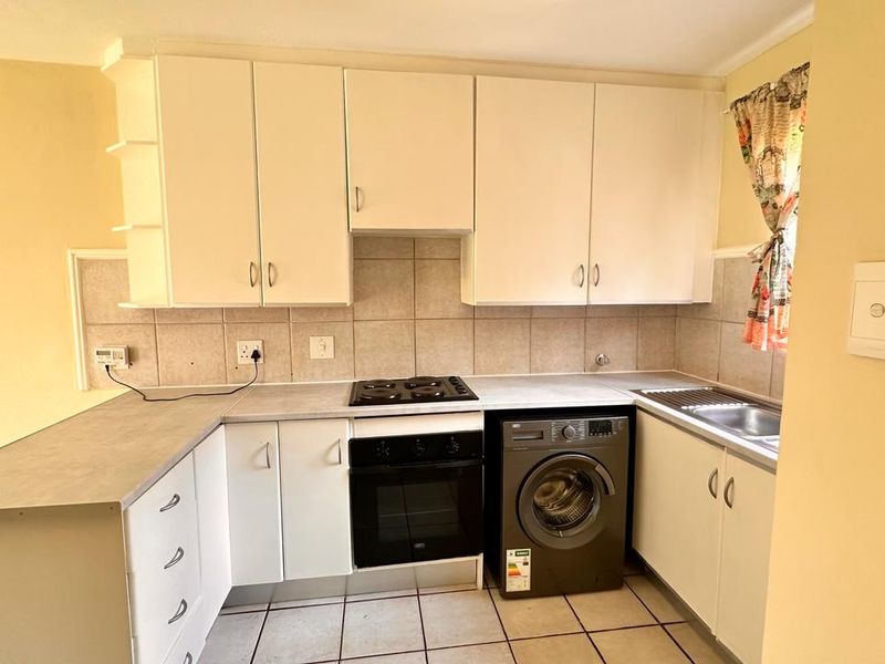 Functional kitchen featuring built-in cabinetry, laminate countertops, electric hob, oven, and tiled flooring, offering a practical layout for daily meal preparation.