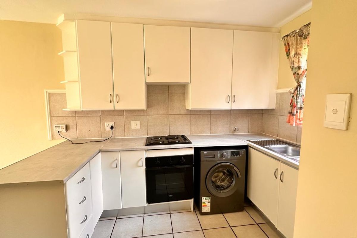 Functional kitchen featuring built-in cabinetry, laminate countertops, electric hob, oven, and tiled flooring, offering a practical layout for daily meal preparation.