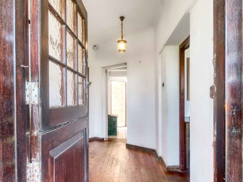 Entrance hallway featuring hardwood flooring, exposed brick accents, and a classic timber door, leading through to the interior living spaces.