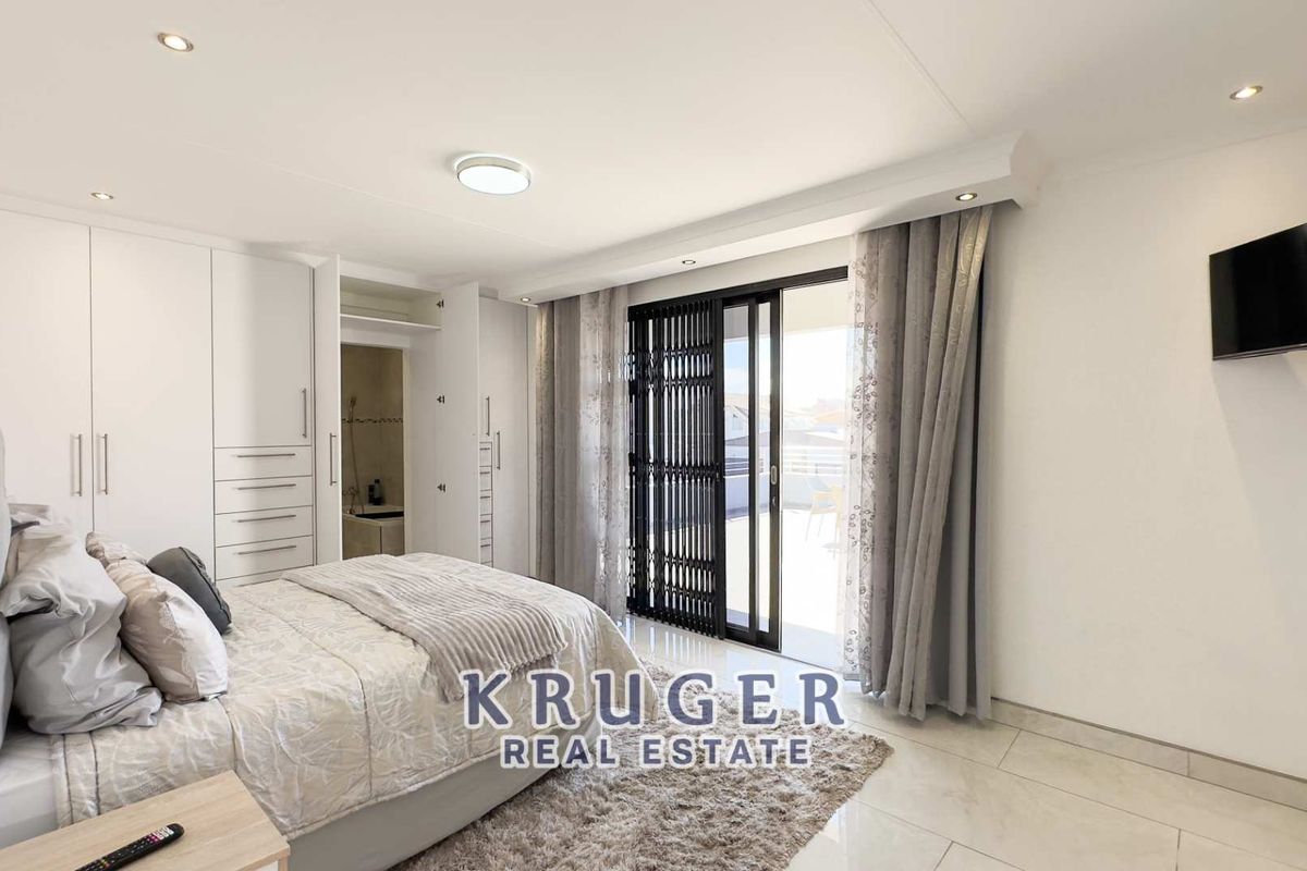 Spacious bedroom featuring built-in wardrobes, tiled flooring, recessed lighting, and sliding glass doors providing direct access to a private balcony.
