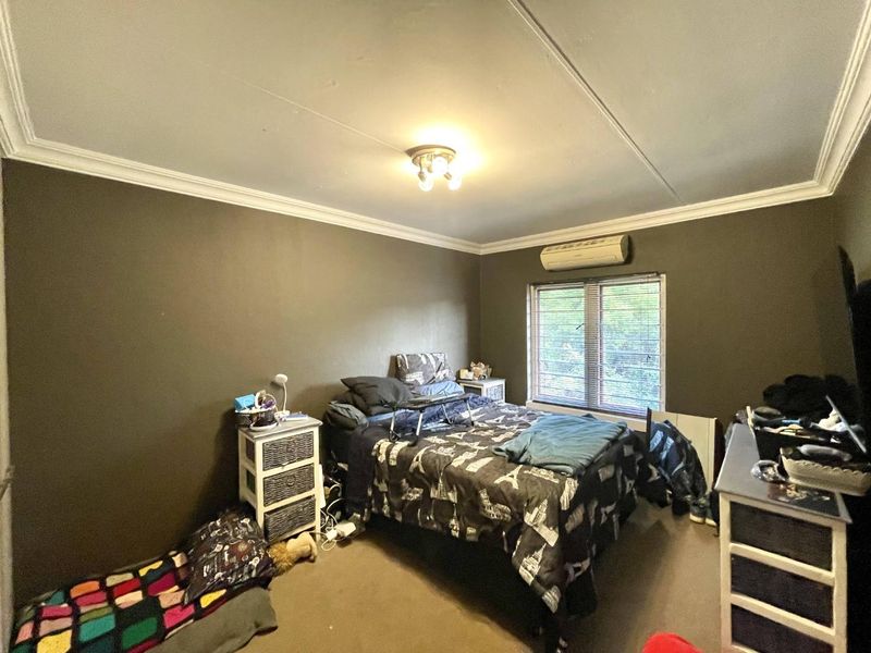 A bedroom featuring a split-system air conditioner, venetian blinds, and decorative ceiling cornicing.