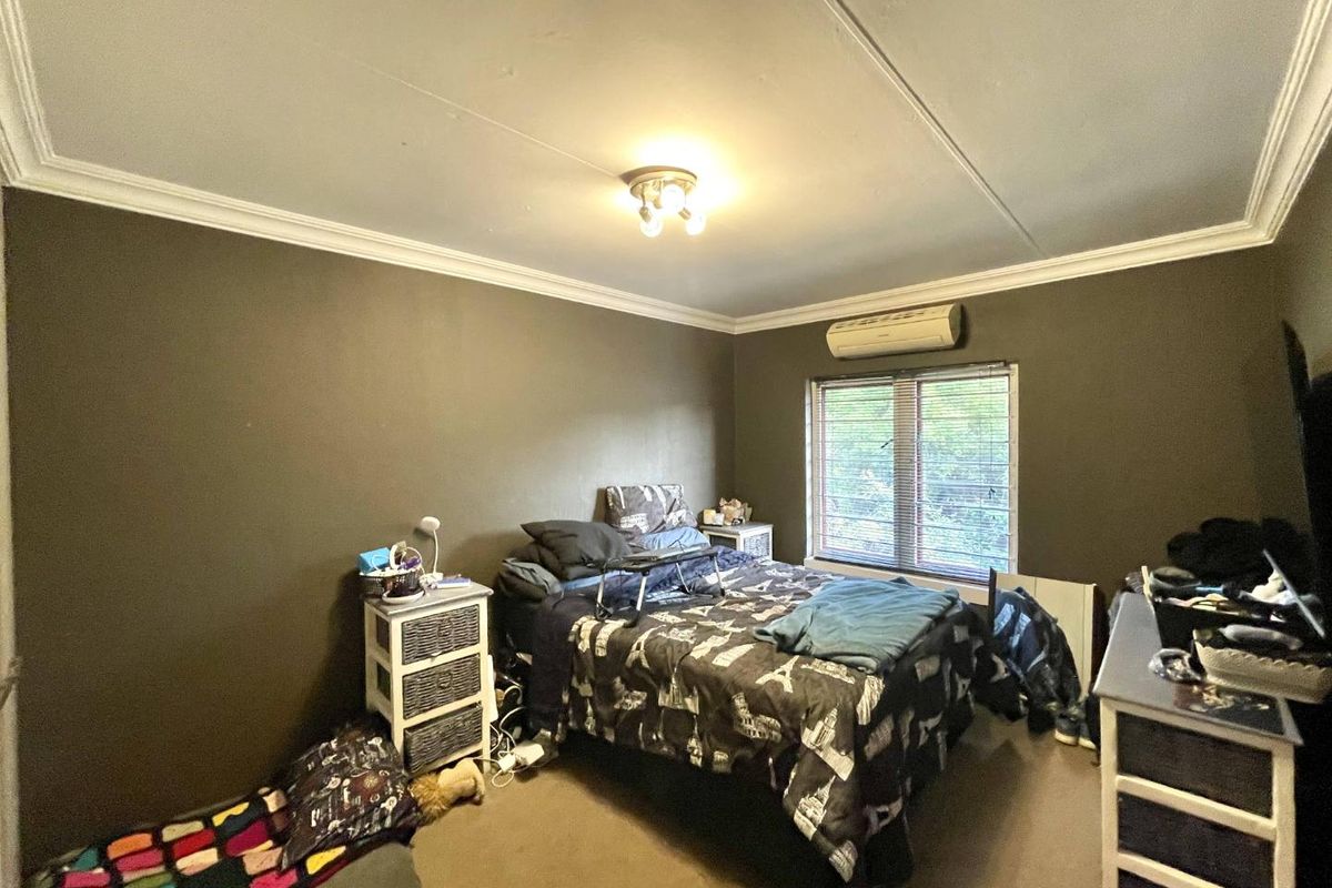 A bedroom featuring a split-system air conditioner, venetian blinds, and decorative ceiling cornicing.
