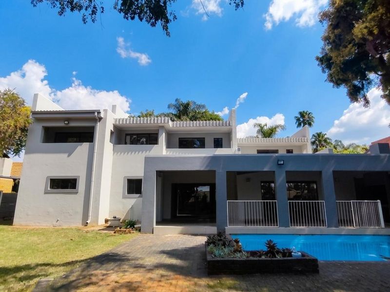 Rear view of the property featuring a swimming pool, paved patio area, and a covered balcony with modern architectural lines.