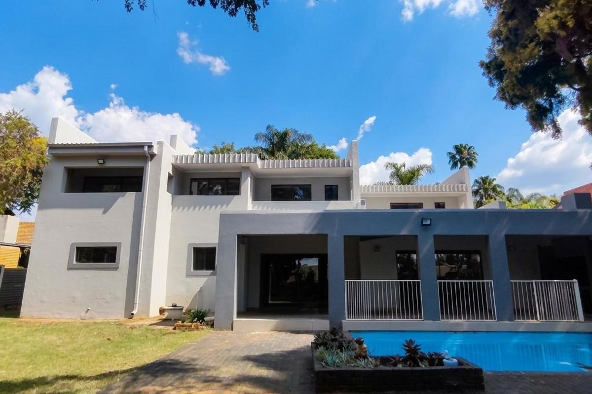 Rear view of the property featuring a swimming pool, paved patio area, and a covered balcony with modern architectural lines.