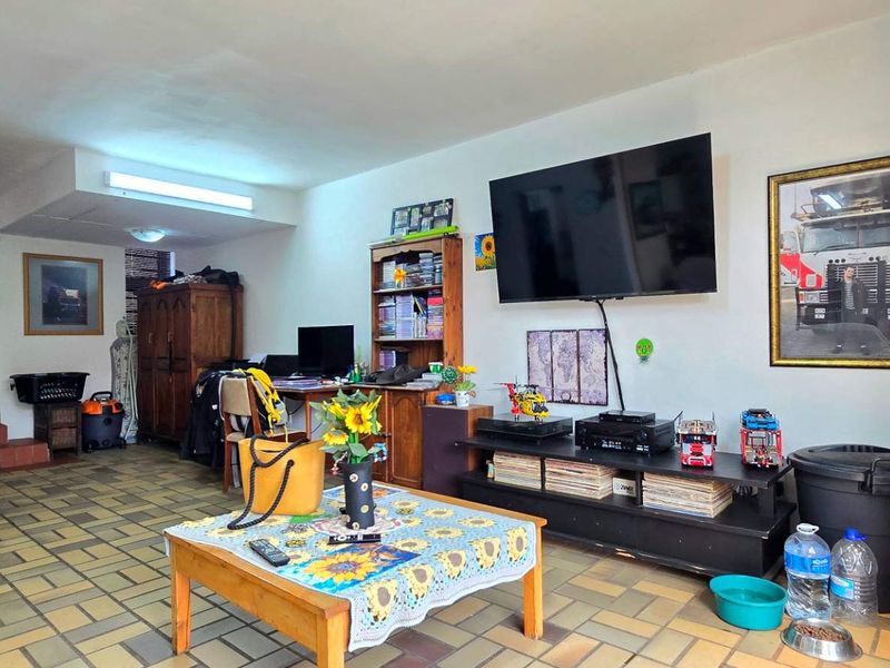 A spacious living area featuring tiled flooring and an internal staircase, providing a functional layout with direct access to the exterior via a security gate.