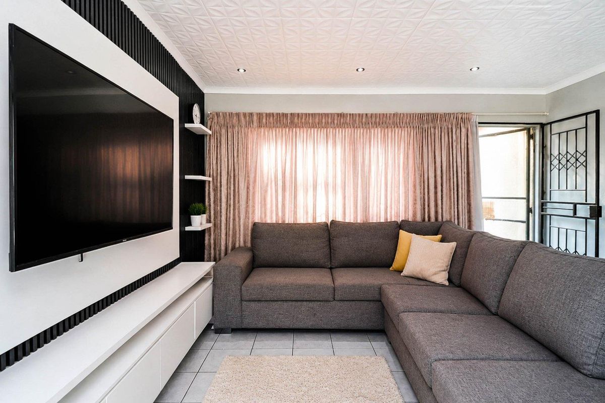 Modern living room featuring a custom black slatted feature wall with integrated cabinetry, tiled flooring, and recessed ceiling lighting.