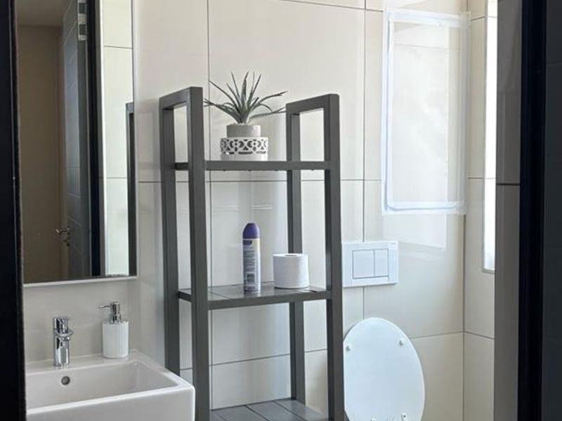 Modern bathroom featuring a wall-mounted basin, wall-hung toilet with concealed cistern, and neutral ceramic tiling throughout.
