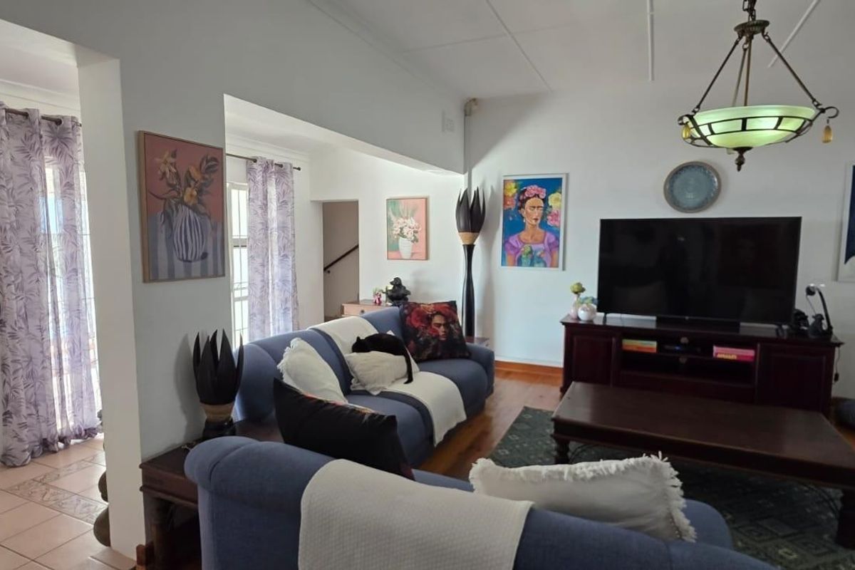 A comfortable living room featuring hardwood flooring, a tiled entryway, and a classic pendant light fixture.