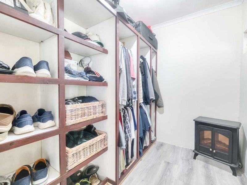 A walk-in closet or dressing area featuring extensive built-in shelving and hanging space, finished with modern laminate flooring.