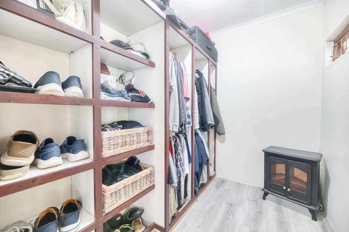 A walk-in closet or dressing area featuring extensive built-in shelving and hanging space, finished with modern laminate flooring.