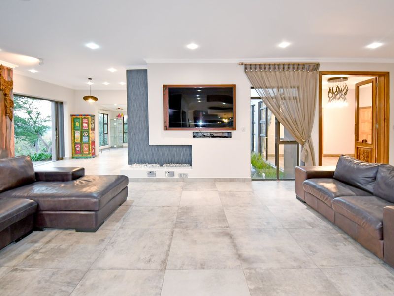 Spacious living room featuring large format floor tiles, recessed lighting, and a modern built-in feature wall with integrated television space.