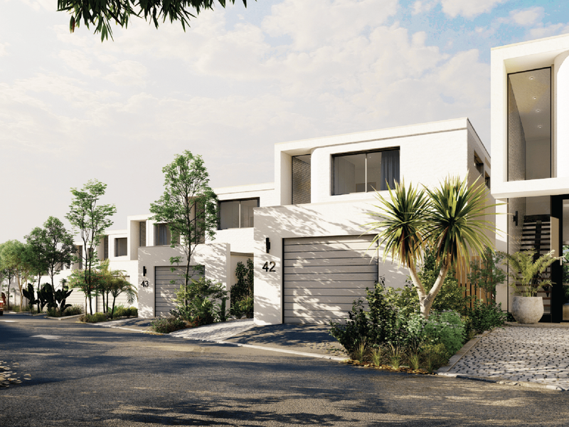 A street-level view of a modern townhouse complex featuring contemporary architectural design, paved driveways, and integrated garage access.