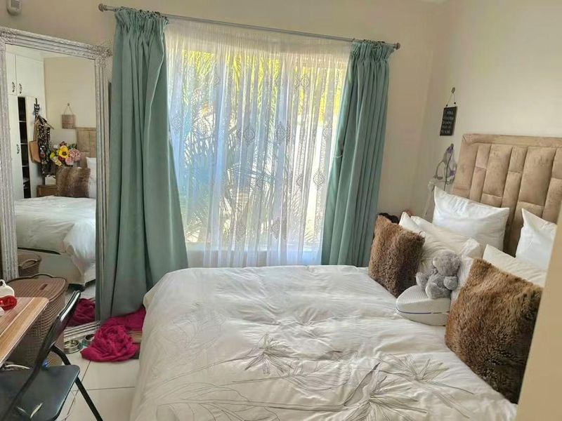 A bedroom featuring tiled flooring, a built-in wardrobe, and a window dressed with curtains, providing a functional living space.