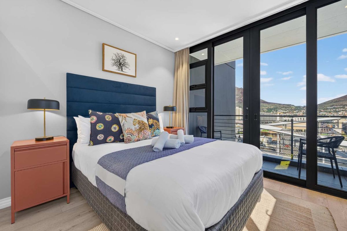 Modern bedroom featuring laminate flooring, recessed lighting, and large sliding glass doors providing direct access to a private balcony with scenic views.