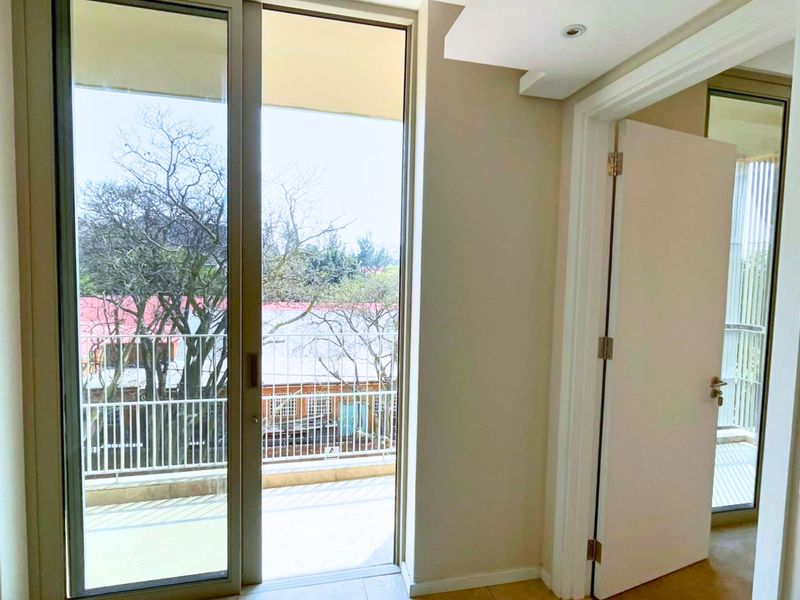 A bright, neutral-toned hallway featuring a sliding glass door that provides access to an outdoor balcony area.
