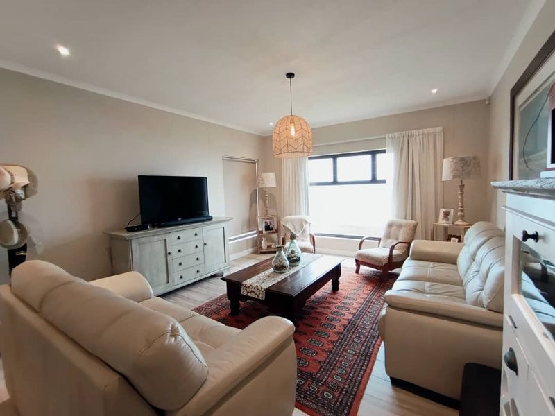 A well-maintained living room featuring neutral wall tones, laminate flooring, and recessed downlighting, creating a comfortable and inviting atmosphere.