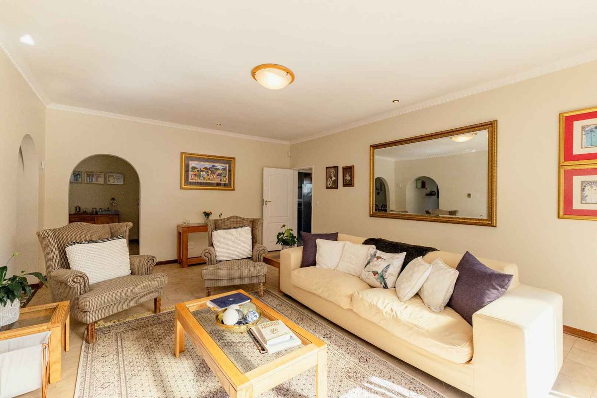 A comfortable living room featuring tiled flooring, coved ceilings, and an arched doorway leading to adjacent spaces.