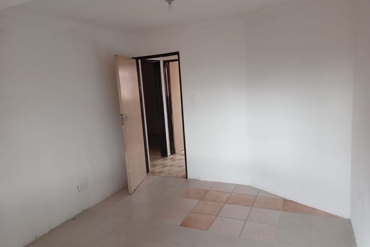 An empty bedroom featuring tiled flooring and a doorway leading to an adjacent room.