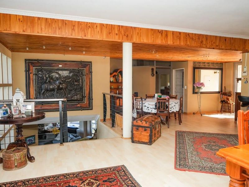 Open plan living area featuring a distinctive timber-clad ceiling, structural column, and laminate flooring, overlooking a lower level staircase.