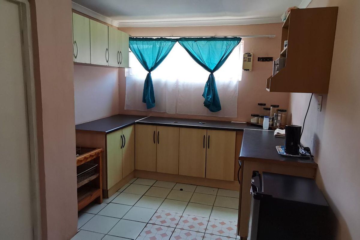 A functional kitchen featuring L-shaped cabinetry, laminate countertops, and tiled flooring, offering a practical layout ready for modernization.