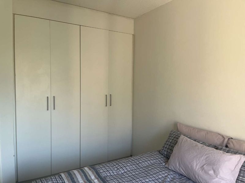 A bedroom featuring a floor-to-ceiling built-in wardrobe with white doors and modern handles.