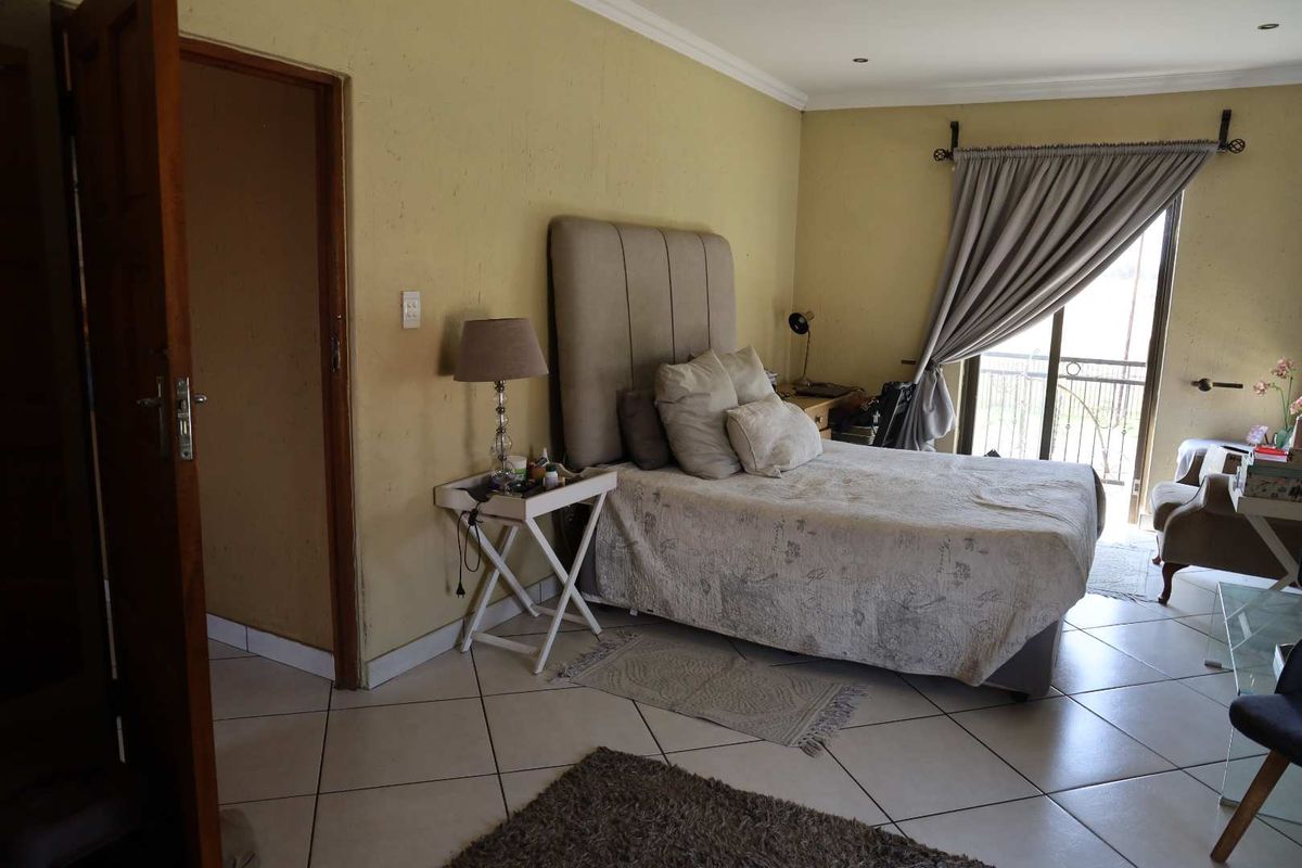 A bedroom featuring tiled flooring, a sliding door leading to a balcony, and neutral wall finishes.