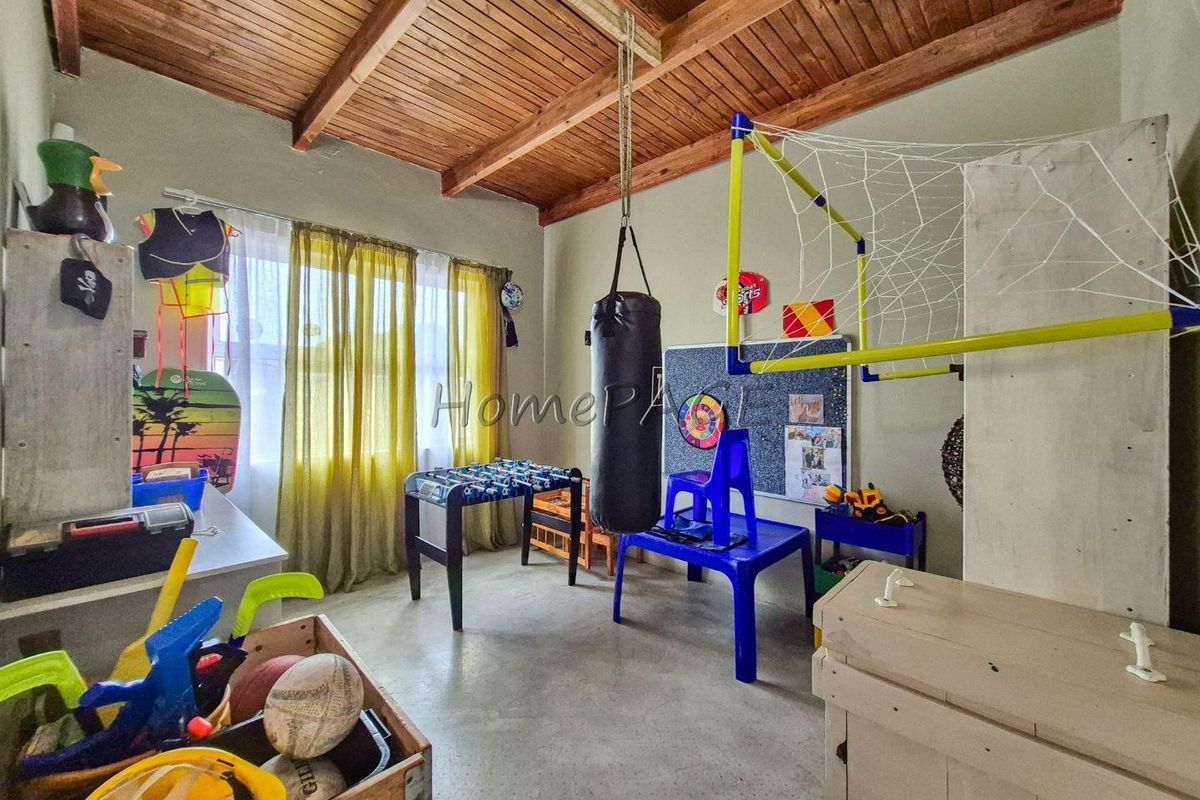 A bedroom featuring exposed timber beam ceilings and concrete flooring, currently utilized as a multi-purpose activity room.