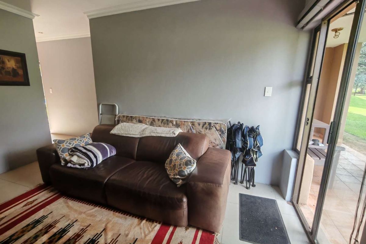 A living room area featuring tiled flooring, crown molding, and large sliding glass doors providing access to an outdoor patio space.
