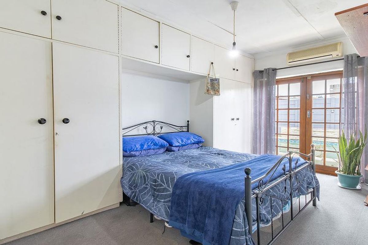 Bedroom featuring extensive built-in cabinetry, a split-system air conditioner, and direct access to the outdoor area through timber-framed glass doors.