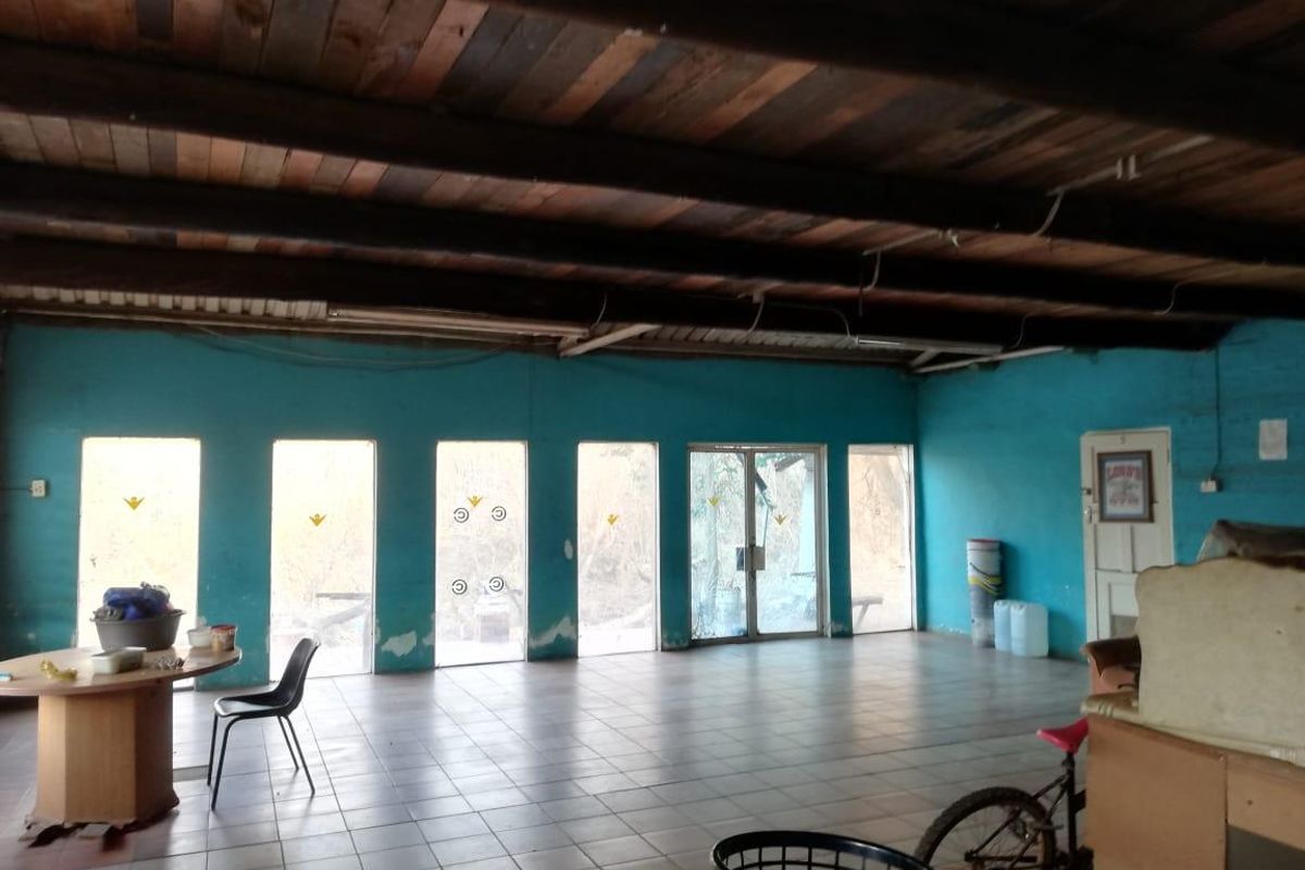 Spacious living area featuring exposed timber beam ceilings, tiled flooring, and large windows providing ample natural light.