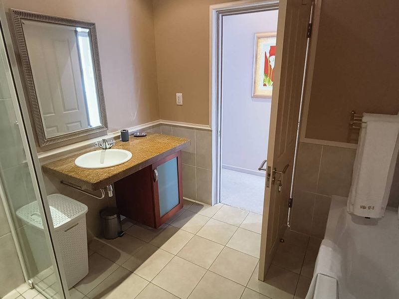 A functional bathroom featuring a vanity with granite countertop, a separate shower enclosure, and a bathtub with tiled finishes.