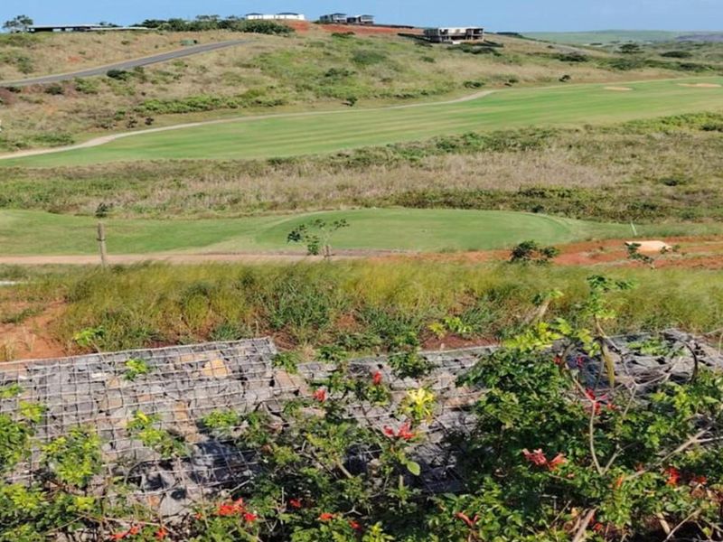 Elevated view overlooking a golf course landscape with a foreground gabion retaining wall.