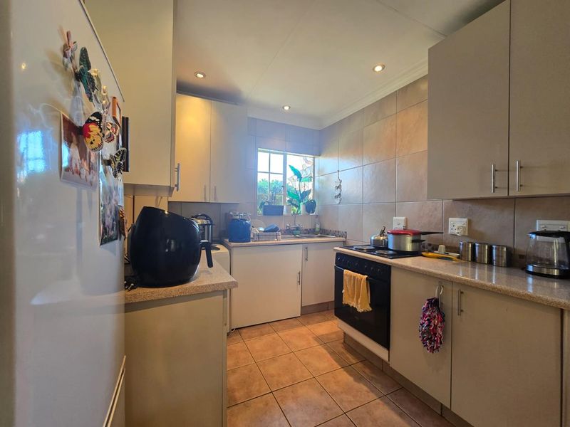A functional kitchen featuring built-in cabinetry, tiled backsplash, laminate countertops, and a freestanding stove, providing a practical workspace with recessed lighting.