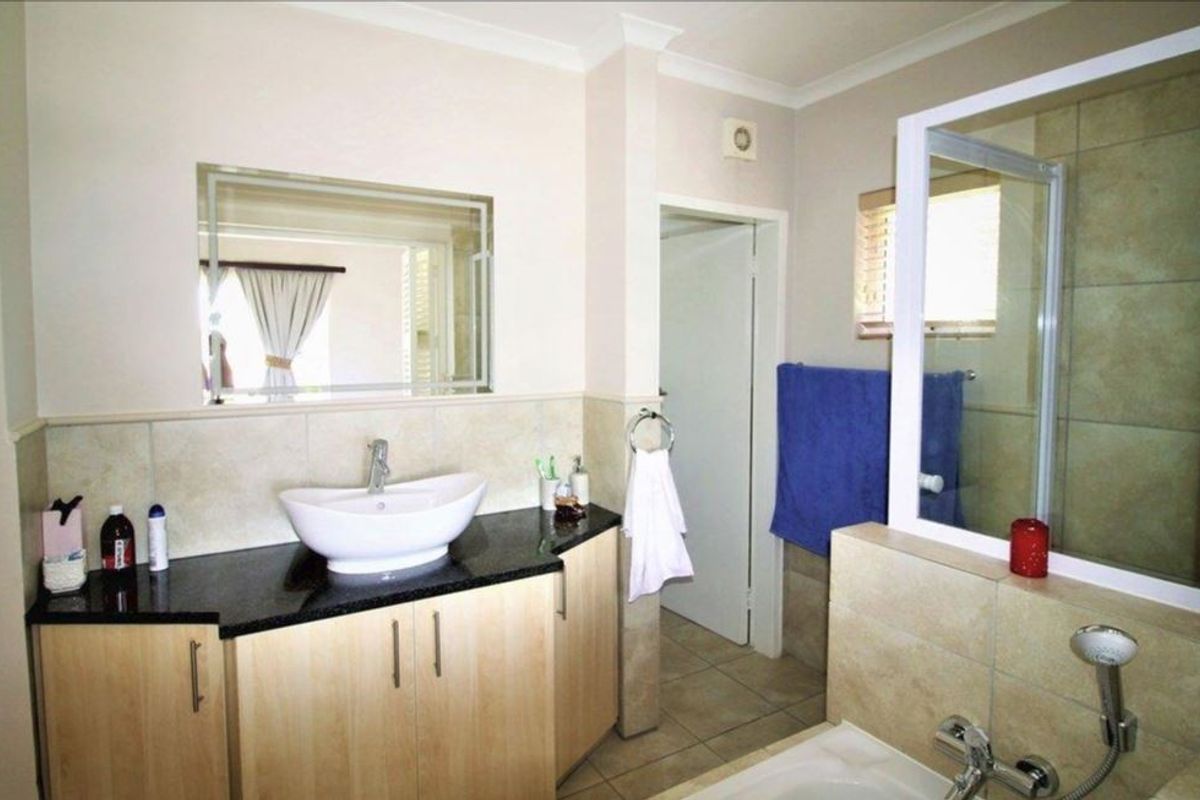 A well-maintained bathroom featuring a modern vessel sink on a granite vanity, tiled walls, and a separate shower enclosure.