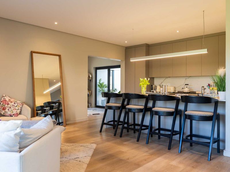 Modern open-plan living area featuring a sleek kitchen with stone countertops, integrated cabinetry, and high-quality hardwood flooring, seamlessly connecting to the living space.