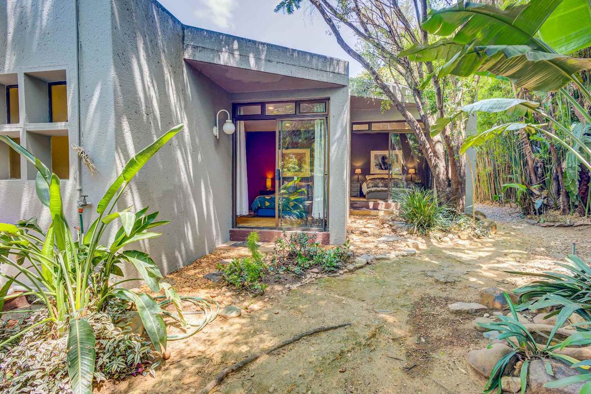 A rear exterior view showing a modern architectural design with large sliding glass doors providing direct access to the garden area.