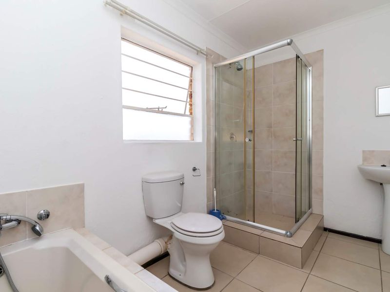 A functional bathroom featuring a shower enclosure, pedestal basin, toilet, and bathtub with tiled flooring and a louver window.