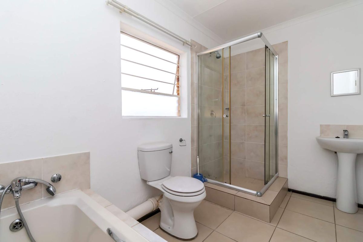 A functional bathroom featuring a shower enclosure, pedestal basin, toilet, and bathtub with tiled flooring and a louver window.