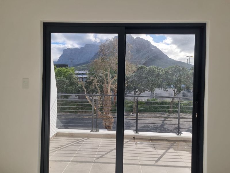 A clean, empty balcony space featuring a modern metal balustrade and sliding glass doors, offering a clear view of the mountain.