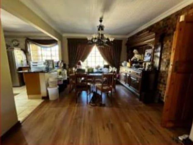 Open plan living and dining area featuring hardwood flooring, an exposed brick wall, and a kitchen with a breakfast island.