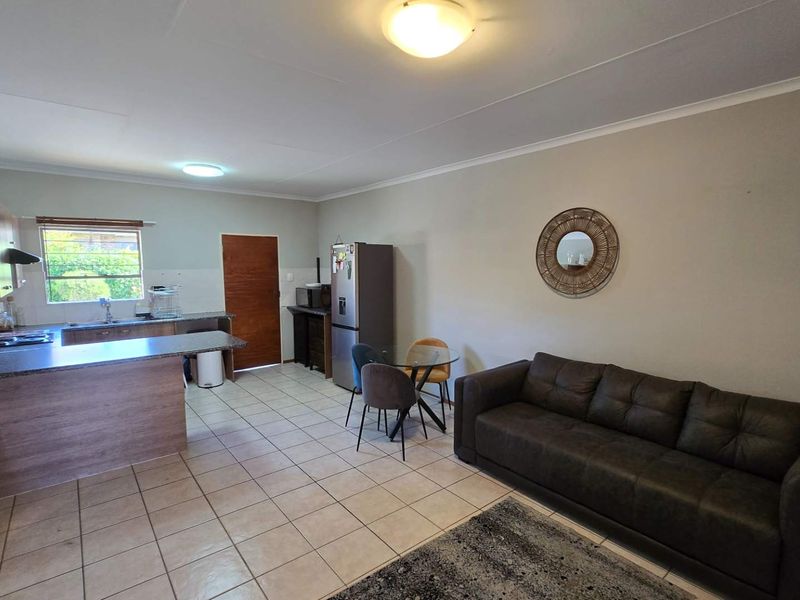 Open-plan living and kitchen area featuring tiled flooring, functional cabinetry, and a breakfast counter, providing a versatile space for daily living.