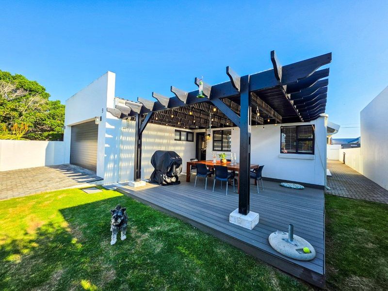 A well-maintained outdoor patio area featuring a timber pergola, composite decking, and direct access to the garage and garden.