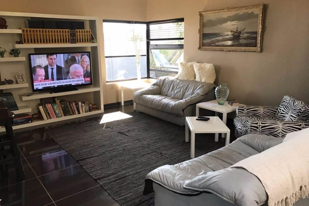 A comfortable living room featuring dark tiled flooring, built-in shelving, and large windows that provide natural light.