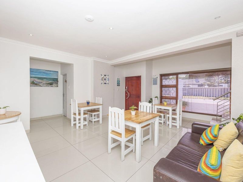 Open-plan living and dining area featuring neutral tiled flooring, recessed lighting, and large windows with timber blinds, offering a bright and functional layout.