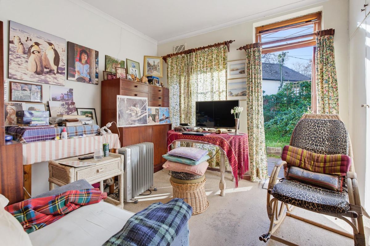 A living room featuring direct access to the rear garden through a glass door, offering potential for renovation and modernization.
