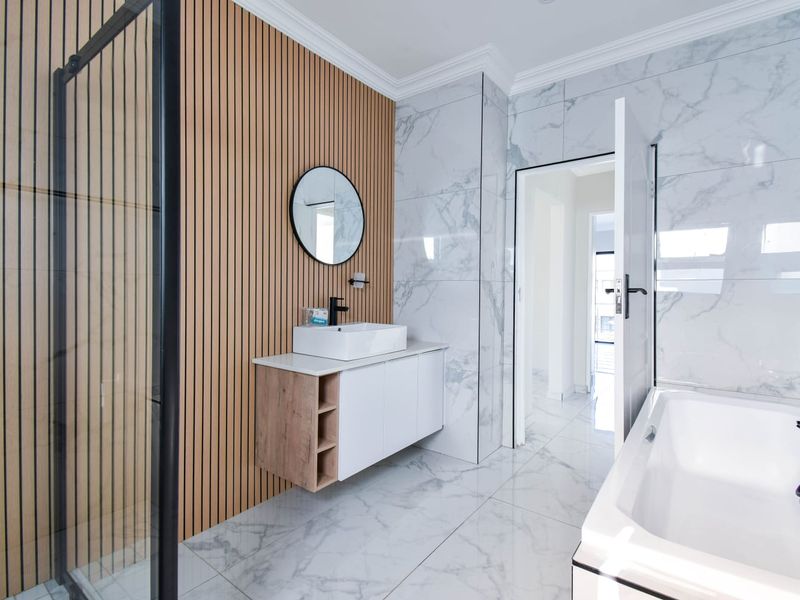 Modern bathroom featuring a floating vanity, vessel sink, slatted timber feature wall, marble-look tiling, glass shower enclosure, and a built-in bathtub.