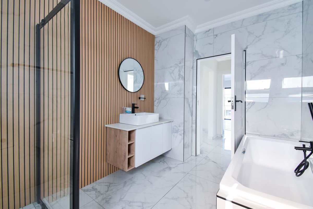 Modern bathroom featuring a floating vanity, vessel sink, slatted timber feature wall, marble-look tiling, glass shower enclosure, and a built-in bathtub.