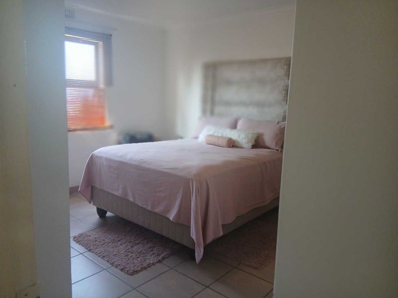 A bedroom featuring tiled flooring and a window with fitted blinds, offering a functional space with neutral wall finishes.
